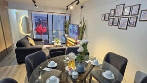 Un comedor moderno con una mesa de vidrio preparada para cuatro personas, rodeada de sillas tapizadas en tono oscuro.