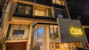 Un edificio de varios pisos con un llamativo letrero de neón, ventanas amplias y una entrada visible.