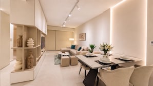 Una sala de estar moderna con sofá, mesa de centro y mesa de comedor lista para una comida.