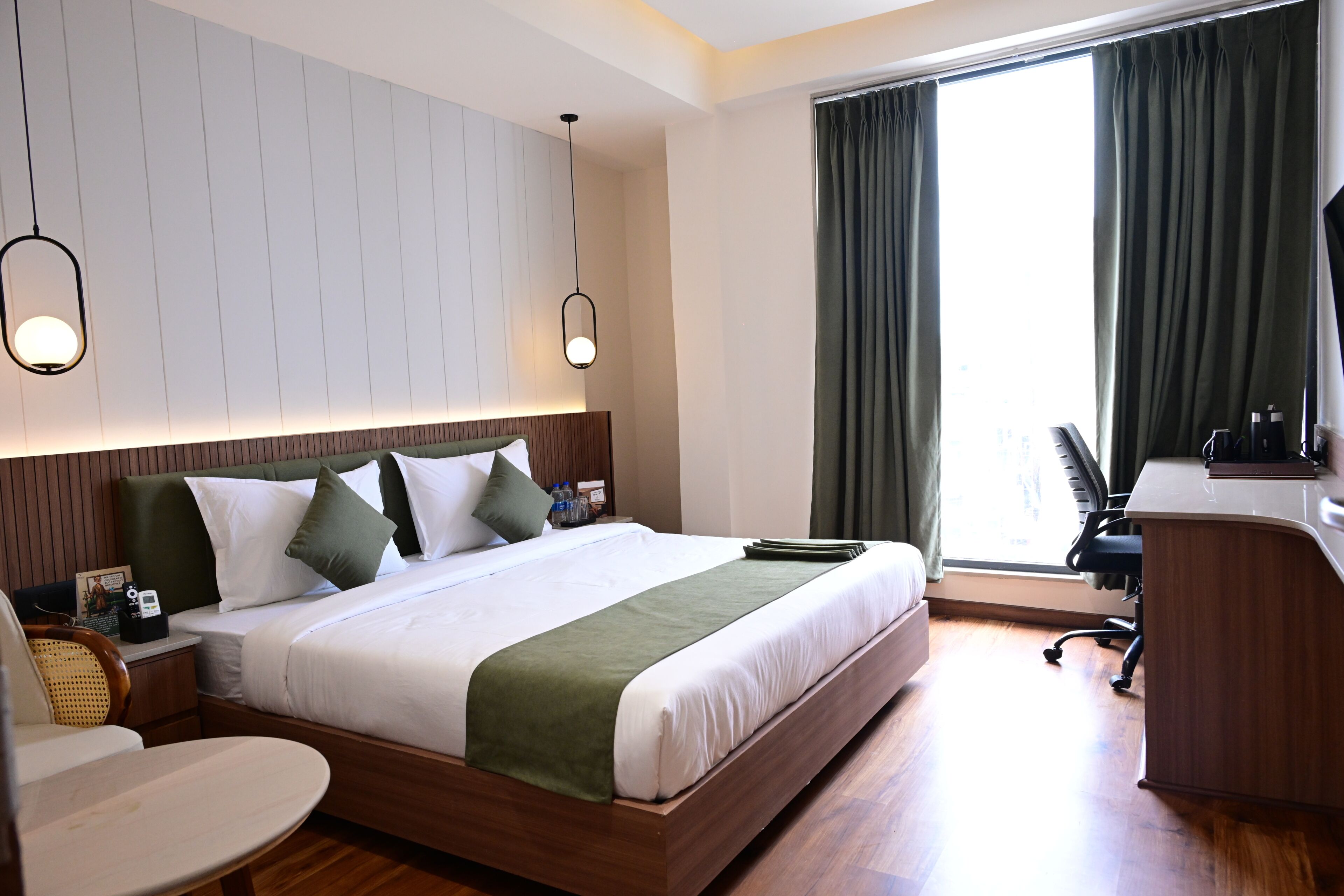 A hotel room with a large bed, a desk, and a chair.