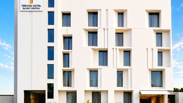 Un moderno edificio hotelero con fachada blanca, múltiples ventanas y cielo despejado.
