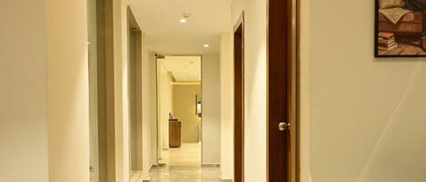 A hallway with a marble floor, a wooden door, and a framed picture on the wall.