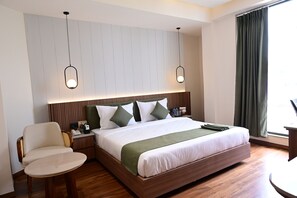 A hotel room with a large bed, two bedside tables, a chair, and a desk. - Trevon Hotel Gujrat Centrale, Ranchi (Ranchi)