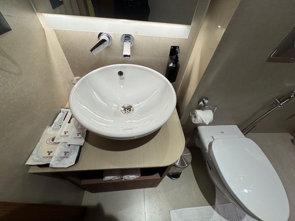 Un bagno con lavandino bianco, WC e specchio sopra il lavandino.