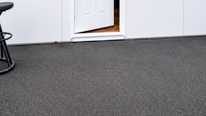 A white building with a door, a small window, and a black object on the wall.