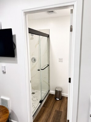 Ein modernes Badezimmer mit Duschkabine aus Glas, Toilette und Mülleimer.