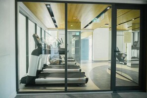 A modern gym with treadmills, exercise equipment, and glass walls. - Cozy 1-bedroom apartment in Laguna Beachside (Thalang District)