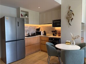 Una cocina moderna con electrodomésticos de acero inoxidable, armarios de madera, microondas integrado y un comedor con una mesa redonda y sillas.