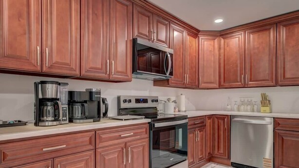 Una cocina con armarios de madera, microondas, cafetera, tostadora y lavavajillas.