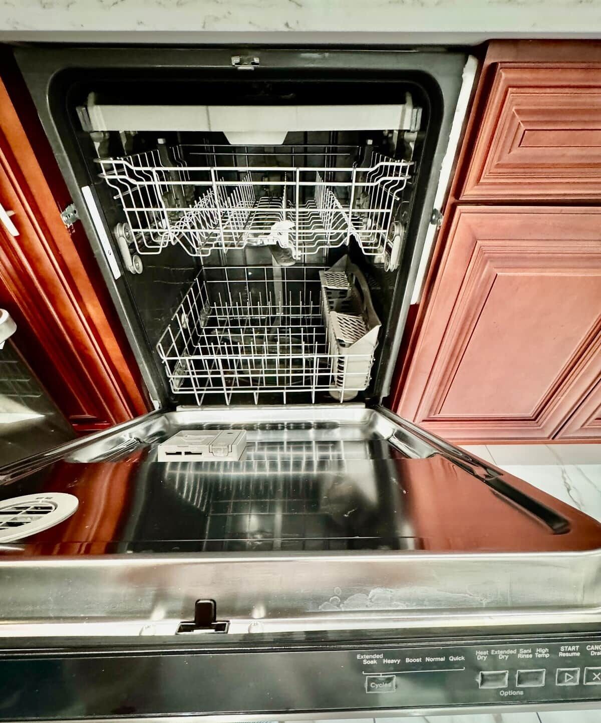 Un lave-vaisselle ouvert, avec ses étagères et son panneau de commande.