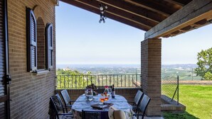 Eine Terrasse im Freien mit Esstisch, Stühlen und Blick auf die Landschaft.