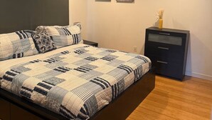 Quarto com uma cama, uma mesa de cabeceira, um aparador e duas imagens penduradas na parede.