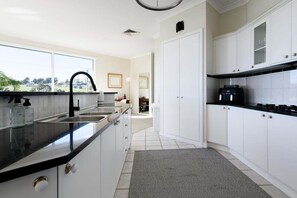 Une cuisine moderne avec un plan de travail noir, des armoires blanches, une cuisinière encastrée et une vue par la fenêtre.