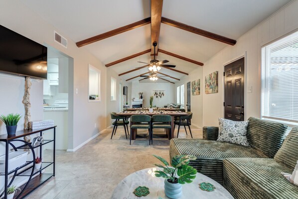 A spacious room with a dining area, a sofa, and a ceiling fan.