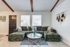 A living room with a sectional sofa, a round coffee table, and a wall-mounted macrame decoration.