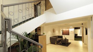 A multi-level interior with a staircase, a sofa, a coffee table, and a potted plant. - Chembur Homeotel - Gagal Home (Mumbai)