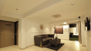 A modern living room with a sectional sofa, a coffee table, and a wall-mounted clock. - Chembur Homeotel - Gagal Home (Mumbai)