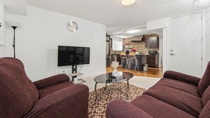 A living room with a TV, two sofas, a coffee table, and a patterned rug.