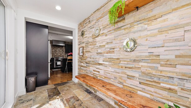 A hallway with a stone wall, a wooden bench, and a trash bin.