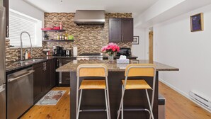 A modern kitchen with a central island, bar stools, and a backsplash.
