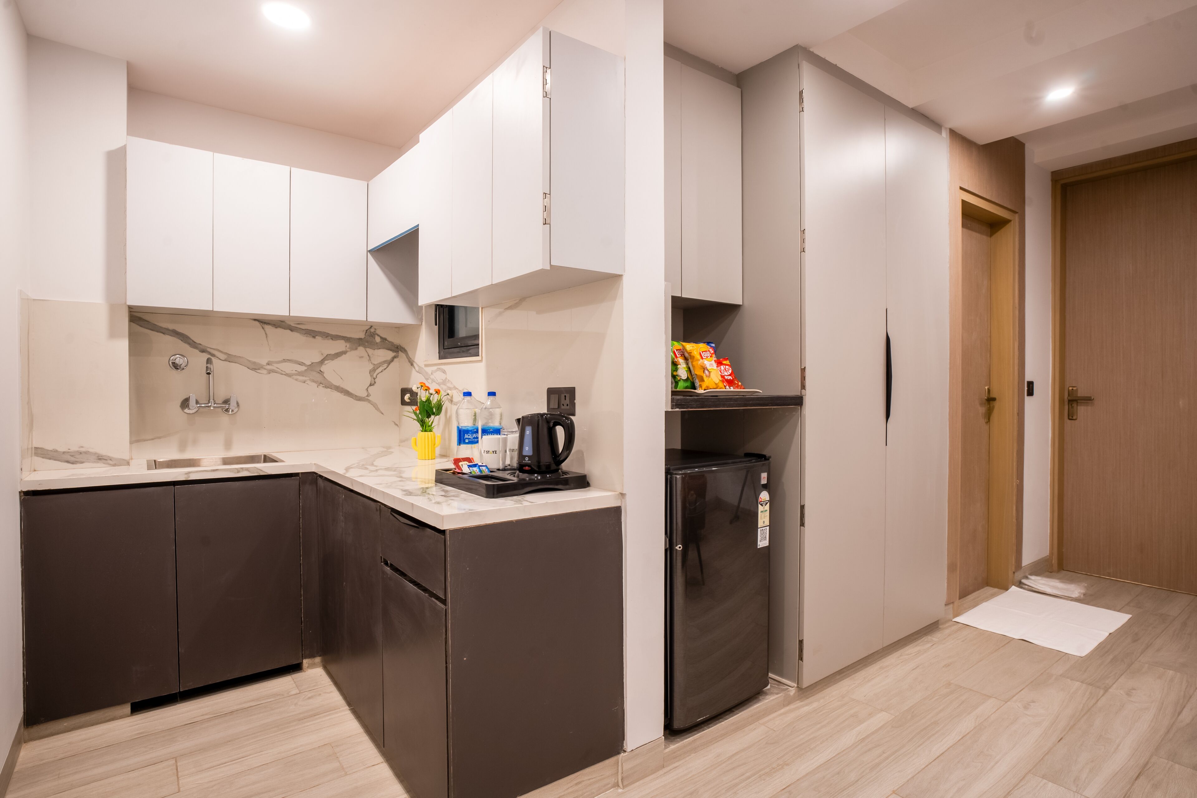 A modern kitchen with dark cabinets, a marble backsplash, and a built-in refrigerator.