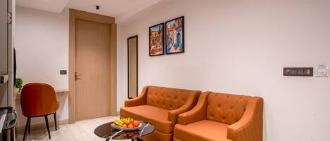 A modern living room with a sofa, a small table with fruit, a red chair, and a ceiling fan.