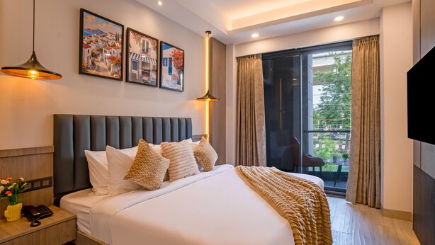 Una habitación de hotel moderna con una cama grande, una mesita de noche, un escritorio y un balcón con cortinas.