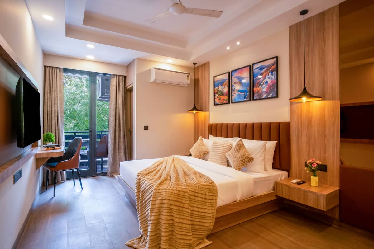 Habitació d'hotel moderna amb llit, escriptori, cadira, televisió i un balcó amb cortines.