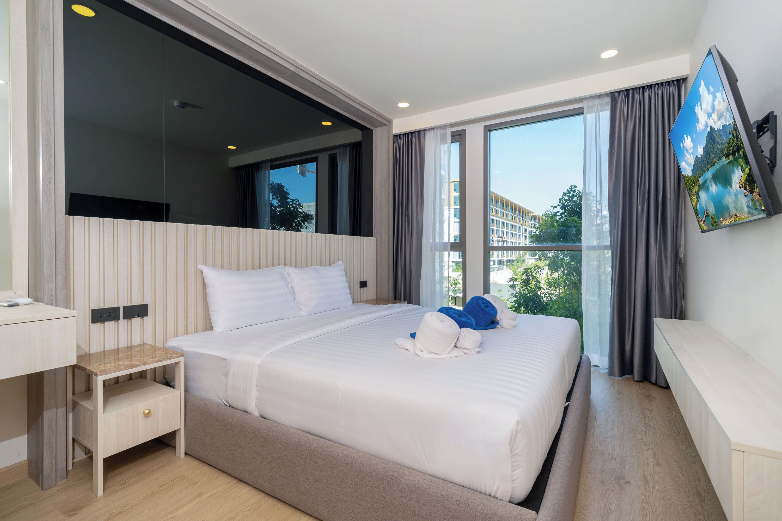 Ein modernes Hotelzimmer mit einem großen Bett, einem Schreibtisch, einem Flachbildfernseher und einem Balkon mit Blick.