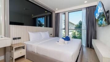 Ein modernes Hotelzimmer mit einem großen Bett, einem Schreibtisch, einem Flachbildfernseher und einem Balkon mit Blick.