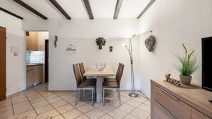 A modern kitchen with a dining area, featuring a tiled floor, wooden cabinets, and a central island with a potted plant. - Apartment 'Beckstedde' with Mountain View, Private Terrace, and Wi-Fi (Arrach)