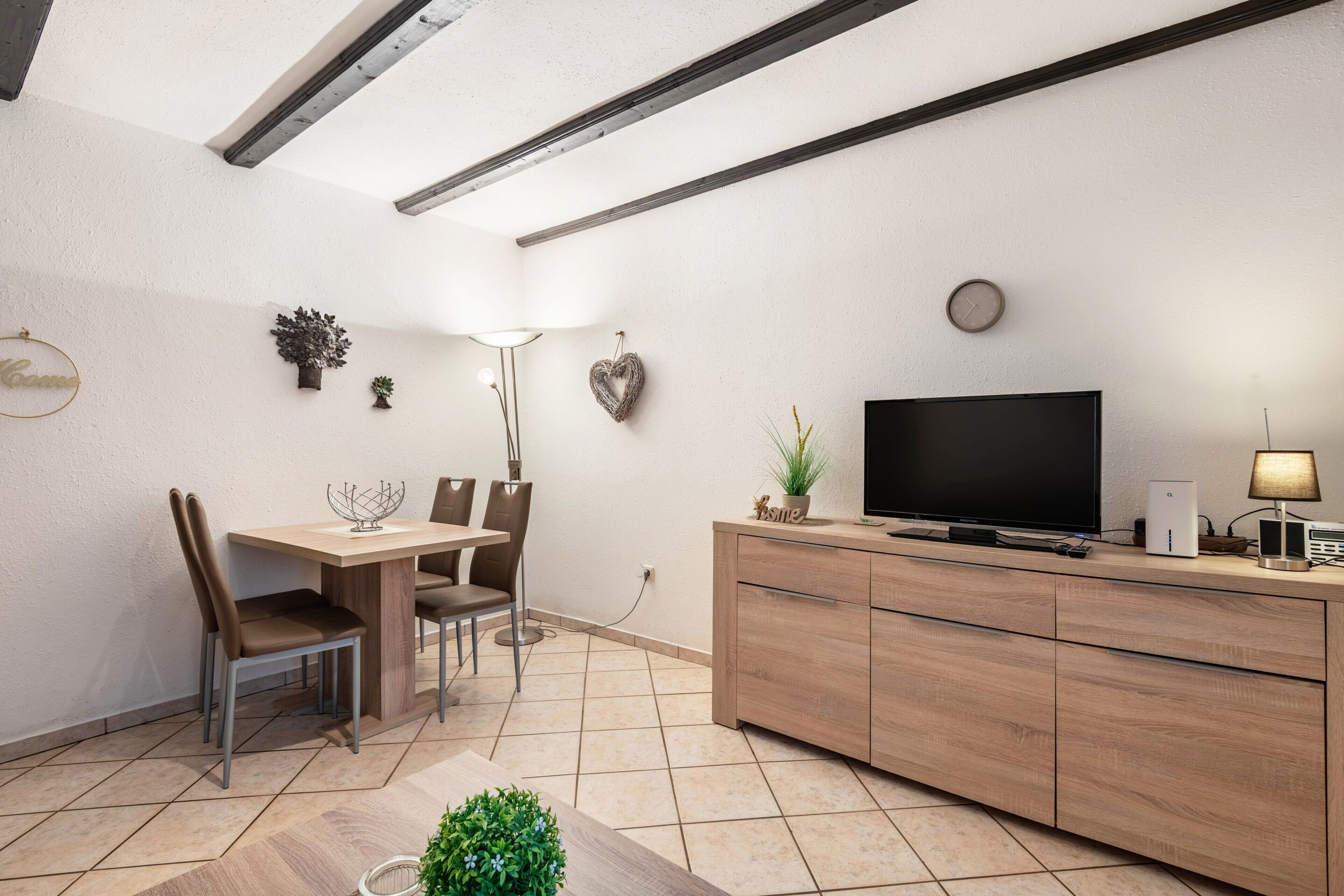 A modern living room with a flat-screen TV, wooden furniture, and decorative wall art.