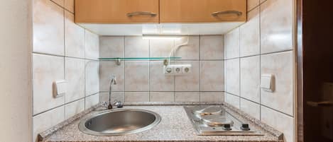 Une cuisine de taille réduite, dotée d’un plan de travail en granit, d’un évier en acier inoxydable et d’une cuisinière à gaz.