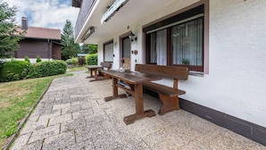 A building with a white exterior, wooden benches, and a gravel pathway. - Apartment 'Beckstedde' with Mountain View, Private Terrace, and Wi-Fi (Arrach)