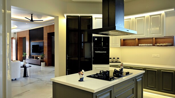A modern kitchen with a central island, built-in appliances, and a dining area with a sofa and table.