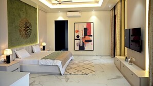 A modern bedroom with a bed, bedside lamps, a ceiling fan, a TV, and artwork on the walls.