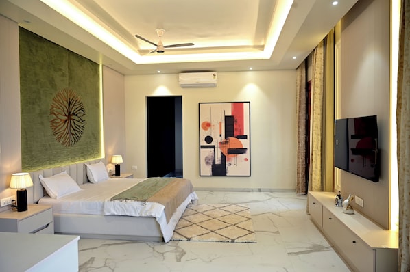 Un dormitorio moderno con cama, lámparas de noche, ventilador de techo, televisión y obras de arte en las paredes.