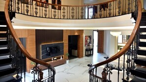 A grand interior with a curved staircase, a fireplace, and a modern living area.