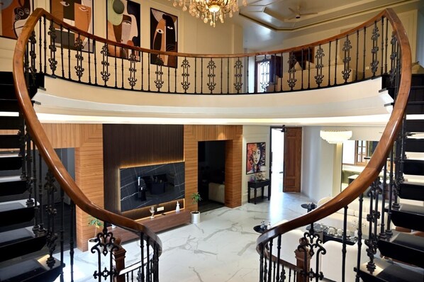 A grand interior with a curved staircase, a fireplace, and a modern living area.