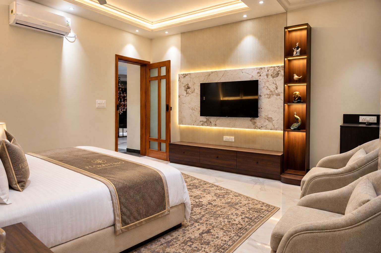 Un dormitorio moderno con una cama grande, un televisor instalado en una pared de mármol, una zona de estar con un sofá y un aparador decorativo.
