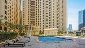 A high-rise building with a swimming pool and lounge chairs.