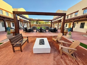 Ein Außenbereich mit einer Holz-Pergola, Sitzgelegenheiten und einer Feuerstelle.