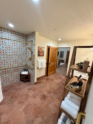 Ein Badezimmer mit einer Dusche, einer Holztür, einem Handtuchhalter und einem Ablagebereich für Toilettenartikel.
