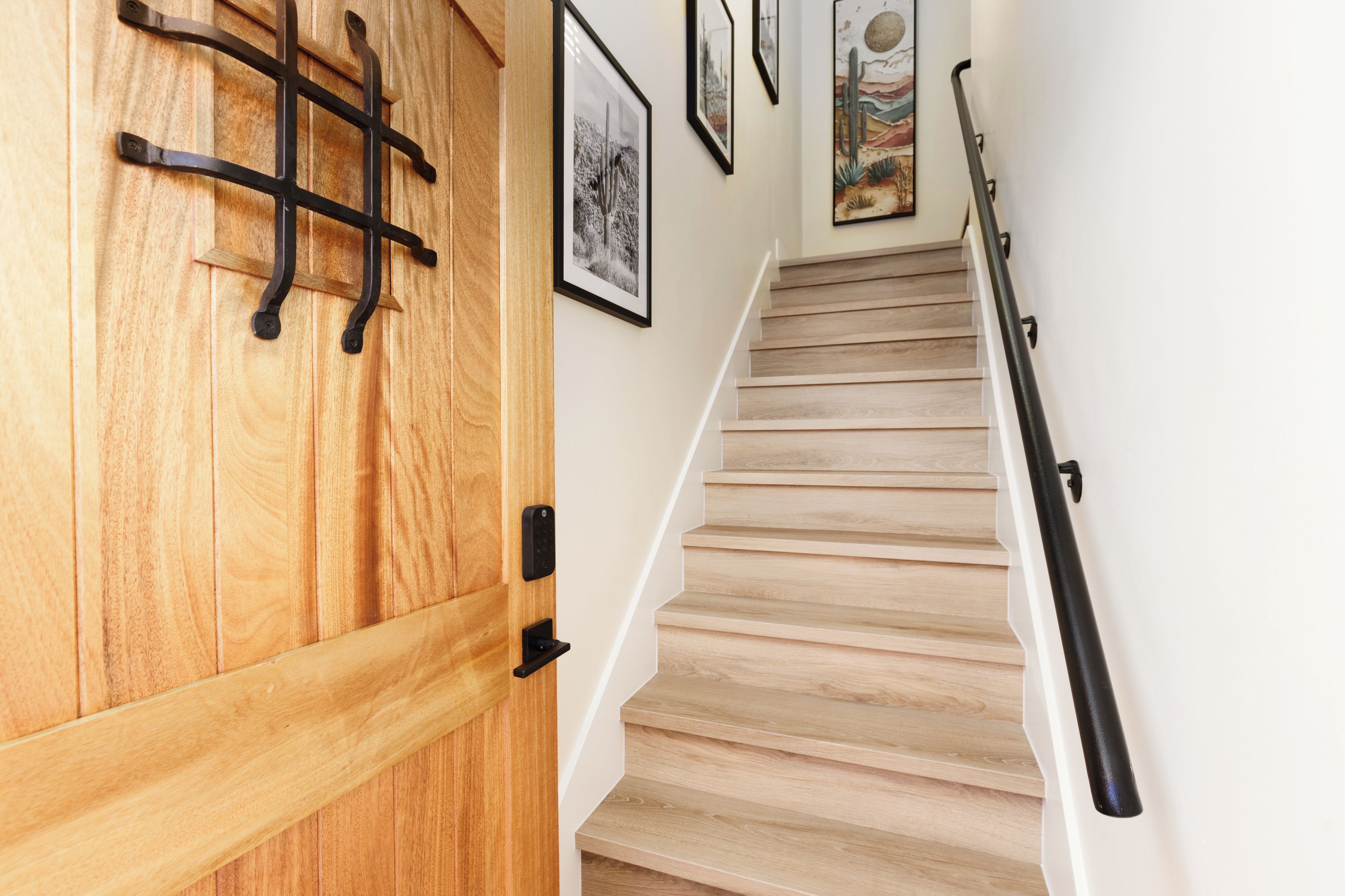 A wooden door with a metal handle and a staircase with a black railing.