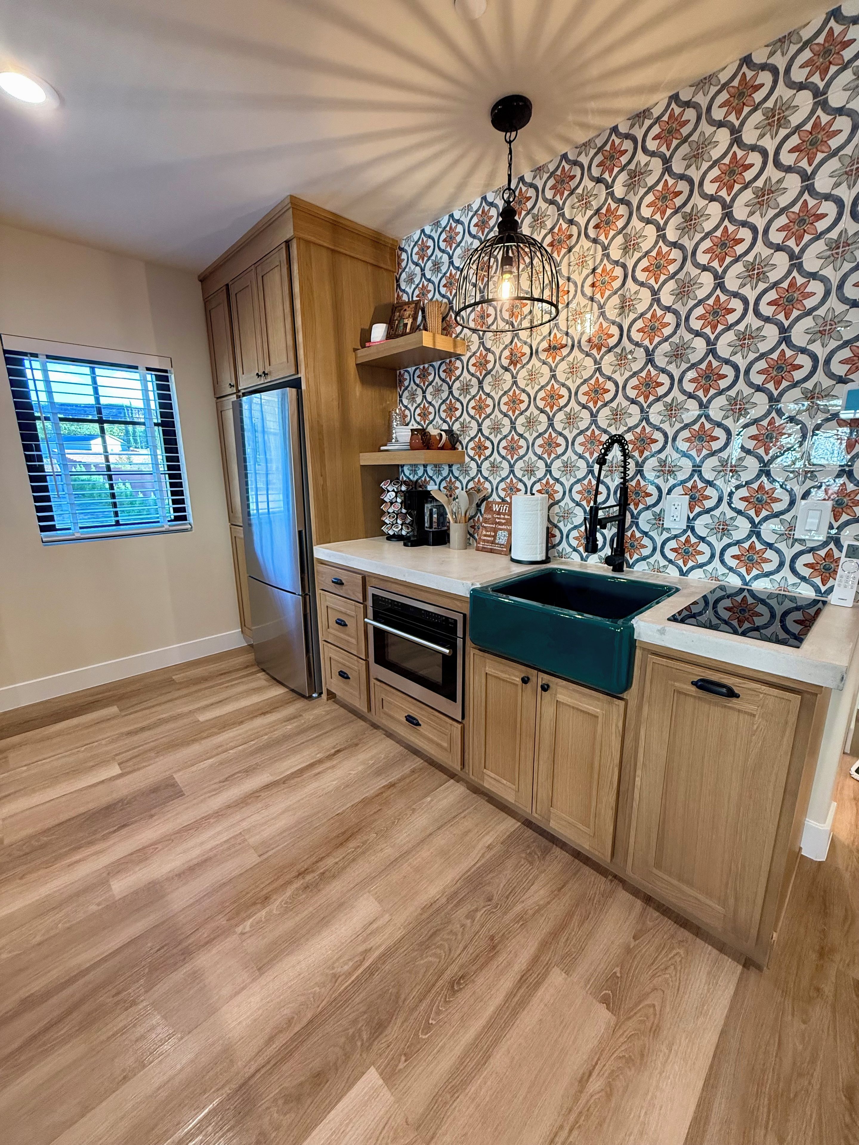 Una cocina con armarios de madera, un refrigerador de acero inoxidable, horno empotrado, un lavamanos y un salpicadero decorativo.