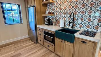Una cocina con armarios de madera, un refrigerador de acero inoxidable, horno empotrado, un lavamanos y un salpicadero decorativo.