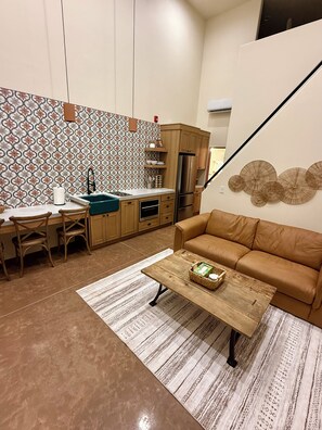 Un espacio habitable funcional con kitchenette, sofá y una mesa de centro.