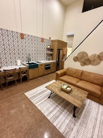 Un espacio habitable funcional con kitchenette, sofá y una mesa de centro.
