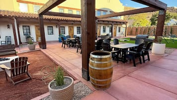 Un patio al aire libre con una pérgola de madera, arreglos de asientos y una parrilla de barbacoa.