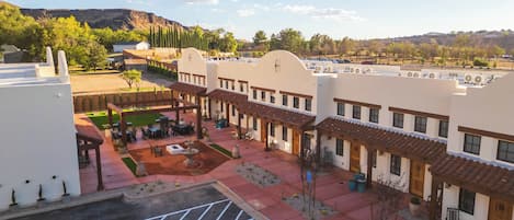 Un patio con mobiliario exterior, un estacionamiento con espacio para discapacitados y edificios de estilo arquitectónico tradicional.